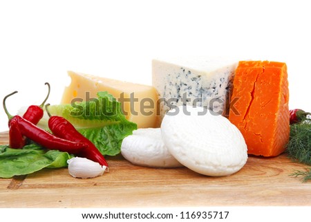 various types of cheese on wooden board with hot peppers and dill isolated over white background
