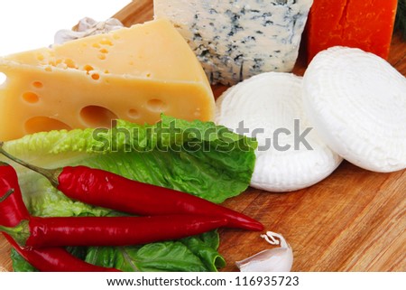 delicatessen french cheese on wooden board with hot peppers and dill isolated on white background