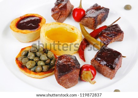 european food: roast beef meat goulash over white plate isolated on white background, with hot pepper, capers and sauces