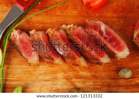 fresh grilled beef meat fillet sliced on wooden board with cutlery isolated  over white background