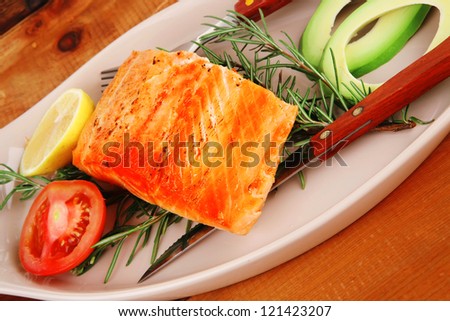 roast fish: hot grilled salmon over glass plate on over wooden table