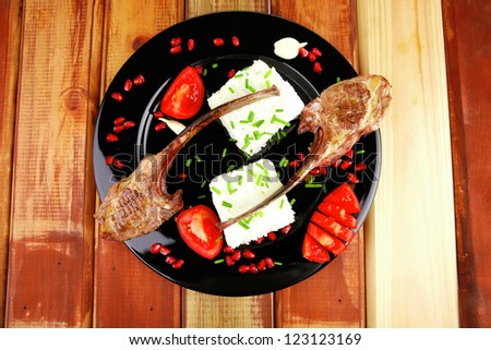 meat food: ribs on black with rice garnish and tomatoes on black on wood
