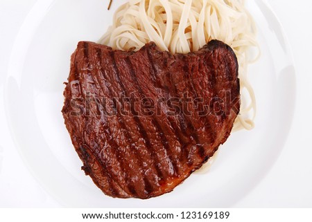 italian food : pasta with tomato on basil and roasted sirloin beef  steak on plate isolated over white background