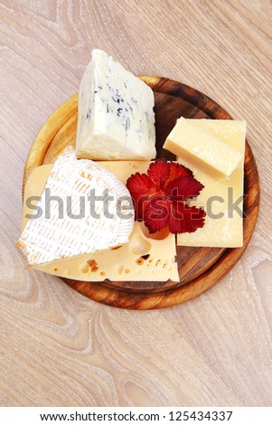 various types of cheese on wooden platter over wooden table
