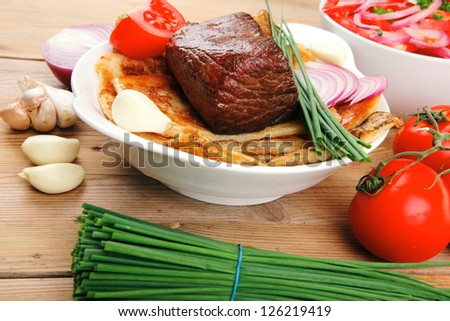 meat : grilled beef fillet mignon on bread with tomatoes salad on wooden table