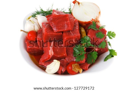 slices of raw fresh beef meat fillet in a white bowls with garlic and red peppers isolated over white background