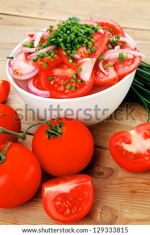 healthy food : fresh tomato salad in white bowl with bunch of chives and raw tomatoes on twig , onion,  over wooden table