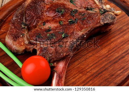 served main course: boned roasted lamb ribs served with green chives and cherry tomato on wooden plate