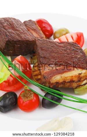 savory food : roast beef garnished with baked apples , green and black olives on white plate isolated over white background
