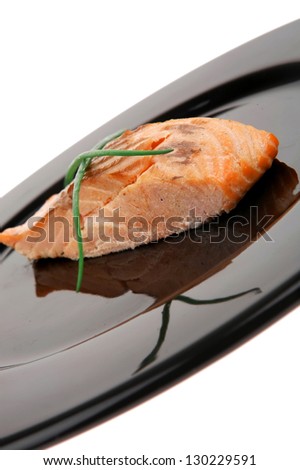 healthy fish cuisine : baked pink salmon steaks with green onion on black dish isolated over white background