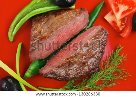 meat food : roast beef fillet mignon served on red plate with apples dill and tomatoes isolated over white background
