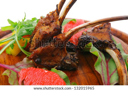 meat food : roast ribs on wooden plate with rocket leaves and grapefruit isolated over white background