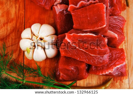 raw fresh beef meat fillet on a wooden plate with dill , hot green red peppers isolated over white background
