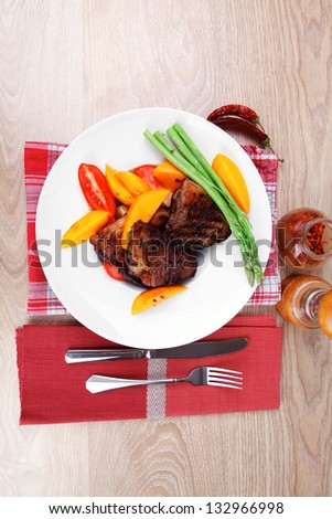 meat food : grilled beef fillet with mango tomatoes and asparagus , served on white dish on red table map over wooden table