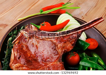 savory : grilled spare rib on dark dish with thyme pepper and tomato on wooden table