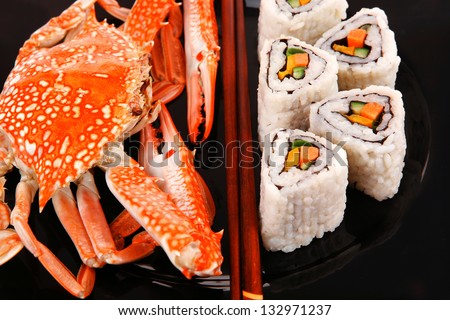 Roll with Cucumber , Cream Cheese with raw Tuna and Salmon inside. on black dish with boiled crab . Japanese traditional Cuisine