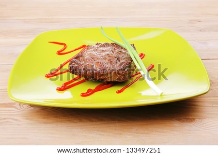 meat food : roasted fillet mignon on green plate with chives and ketchup over wooden table