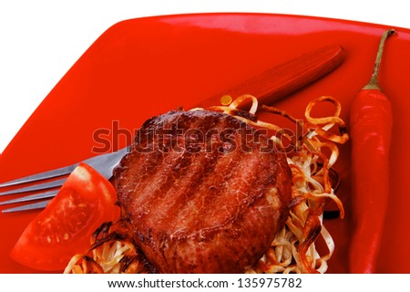 grilled beef fillet pieces on noodles , red hot chili pepper and tomato on red plate isolated over white background