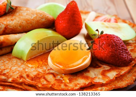 sweet food : big thin pancake with honey strawberries and apple on wooden table