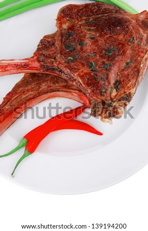 meat savory : grilled beef ribs served with green chives and raw red chili peppers on white dish isolated over white background