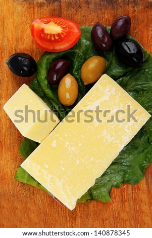 parmesan cheese on wooden platter with olives and tomato isolated over white background