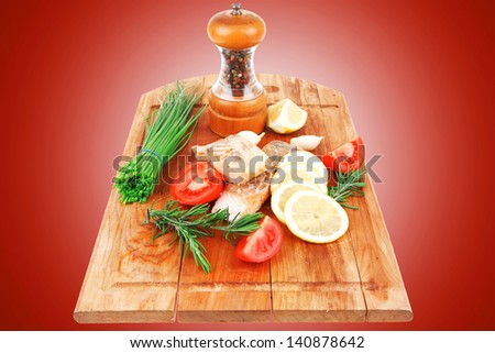 savory sea fish entree : roasted salmon fillet with green onion, red cherry tomatoes pieces, glass pepper grinder, rosemary twigs and lemon on wooden board isolated on white background