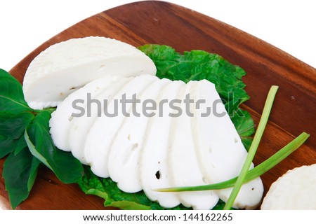 mediterranean dairy  : fresh raw white soft greek feta cheese round and slices on wooden plate isolated over white background