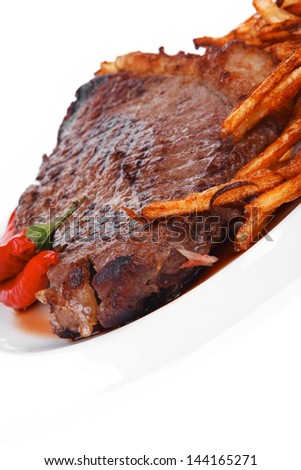entree : grill beef meat steak on white round plate with dry hot chili pepper and potato chips isolated on white background