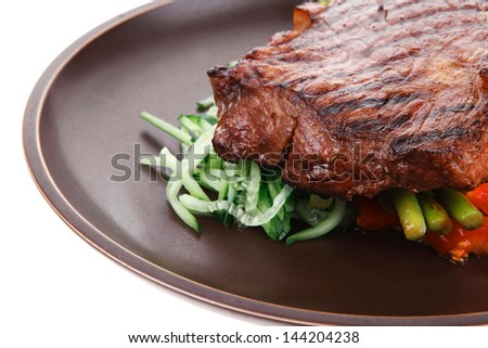 meat table : grilled beef fillet with asparagus and tomatoes served on dish isolated over white