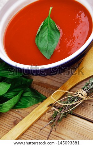 diet food : fresh cold tomato soup with basil thyme and dry pepper in big bowl on wood table