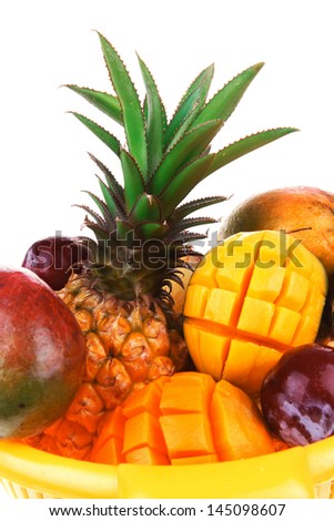 diet food - set of lot of tropical fruits include pineapple plum and mango in orange colander isolated over white background
