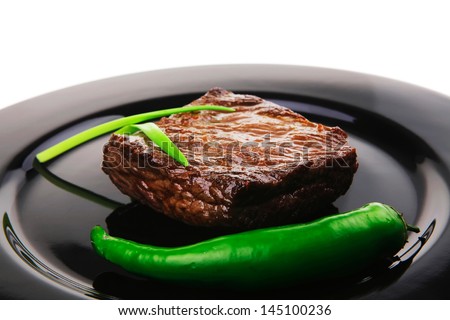 meat savory : grilled beef fillet mignon served on black plate isolated over white background with chili pepper