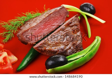 meat food : roasted fillet mignon on red plate with tomatoes apples and chili pepper isolated over white background