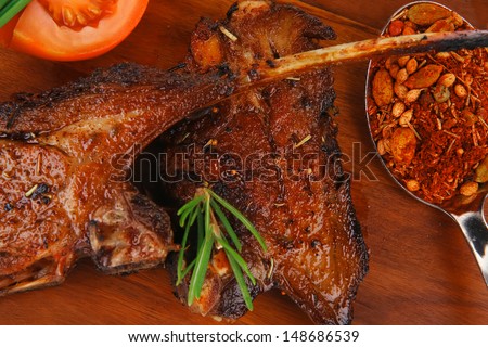 meat savory on wooden plate: roast ribs with peppers tomato and dry spices isolated on white