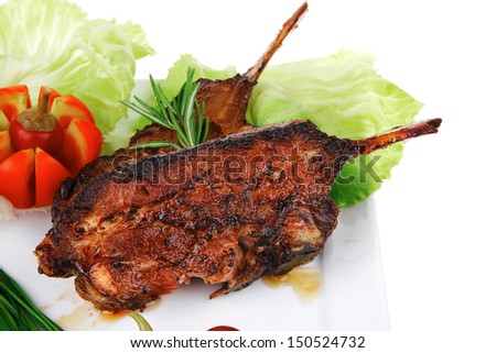 meat savory: roast ribs on white plate with peppers lettuce tomato and chives over white background