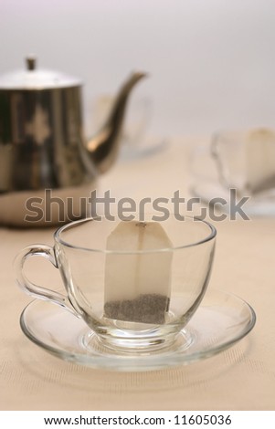 tea pot with transparent tea cup and tea bag inside