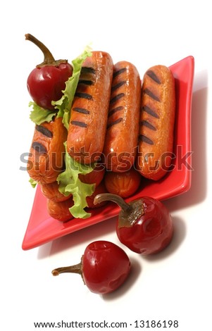 grilled sausages on red dish with small red hot peppers