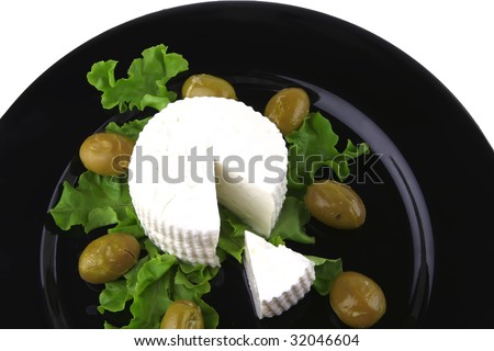 soft feta cheese on black dish with gold olives