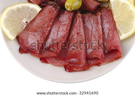 sliced served sausage with green olives and raw lemon