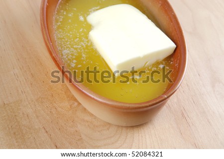 melted butter in small brown bowl on wood