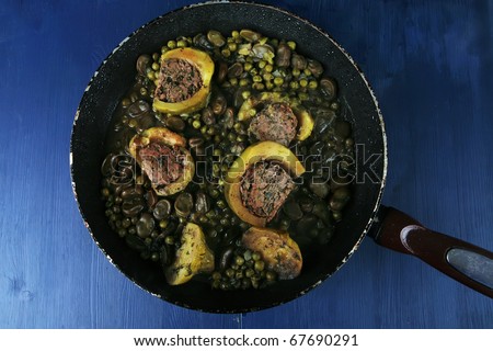 homemade cuisine: zucchini filled meat on peas and beans cooked into pan over blue wood