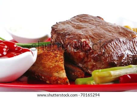 grilled bbq meat with spices and toast bread on red dish isolated over white . shallow dof