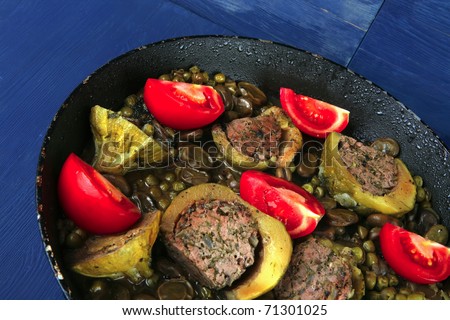 homemade cuisine: zucchini filled meat cooked with peas and tomatoes on black pan
