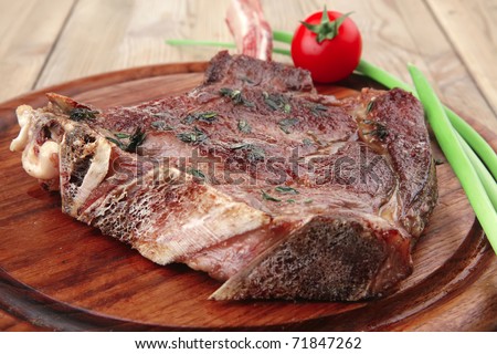 meat savory : grilled beef ribs served with green chives and cherry tomato over wood . shallow dof