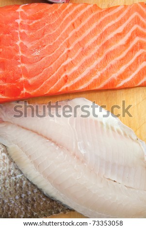fresh raw salmon , red tuna , and sole fish pieces over wooden board isolated on white background