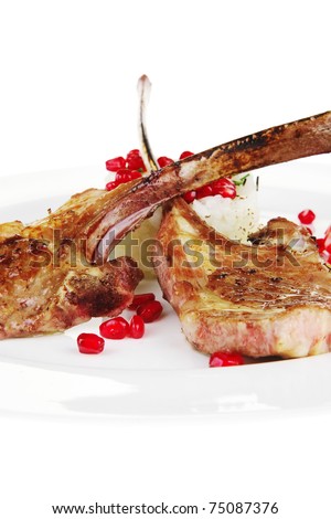 meat savory: roast veal ribs with rice garnish and pomegranate seeds over white background. shallow dof