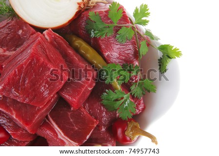 slices of raw fresh beef meat fillet in a white bowls with garlic and red peppers isolated over white background