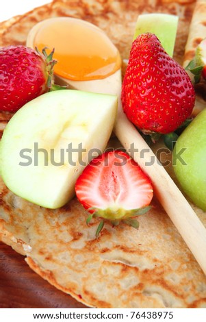 sweet food : big thin pancake with honey strawberries and apple isolated over white background