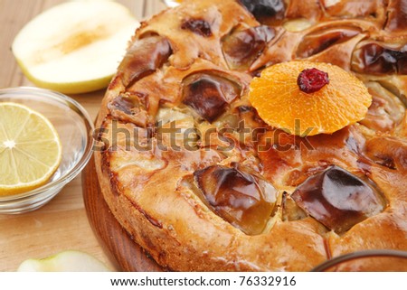 baked food : big apple pie served with fresh apples, raw lemon and mandarin,  tea cup on wooden plate over table