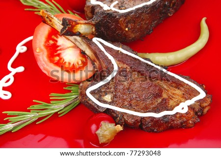 served savory plate: meat ribs on red with tomatoes and red hot peppers